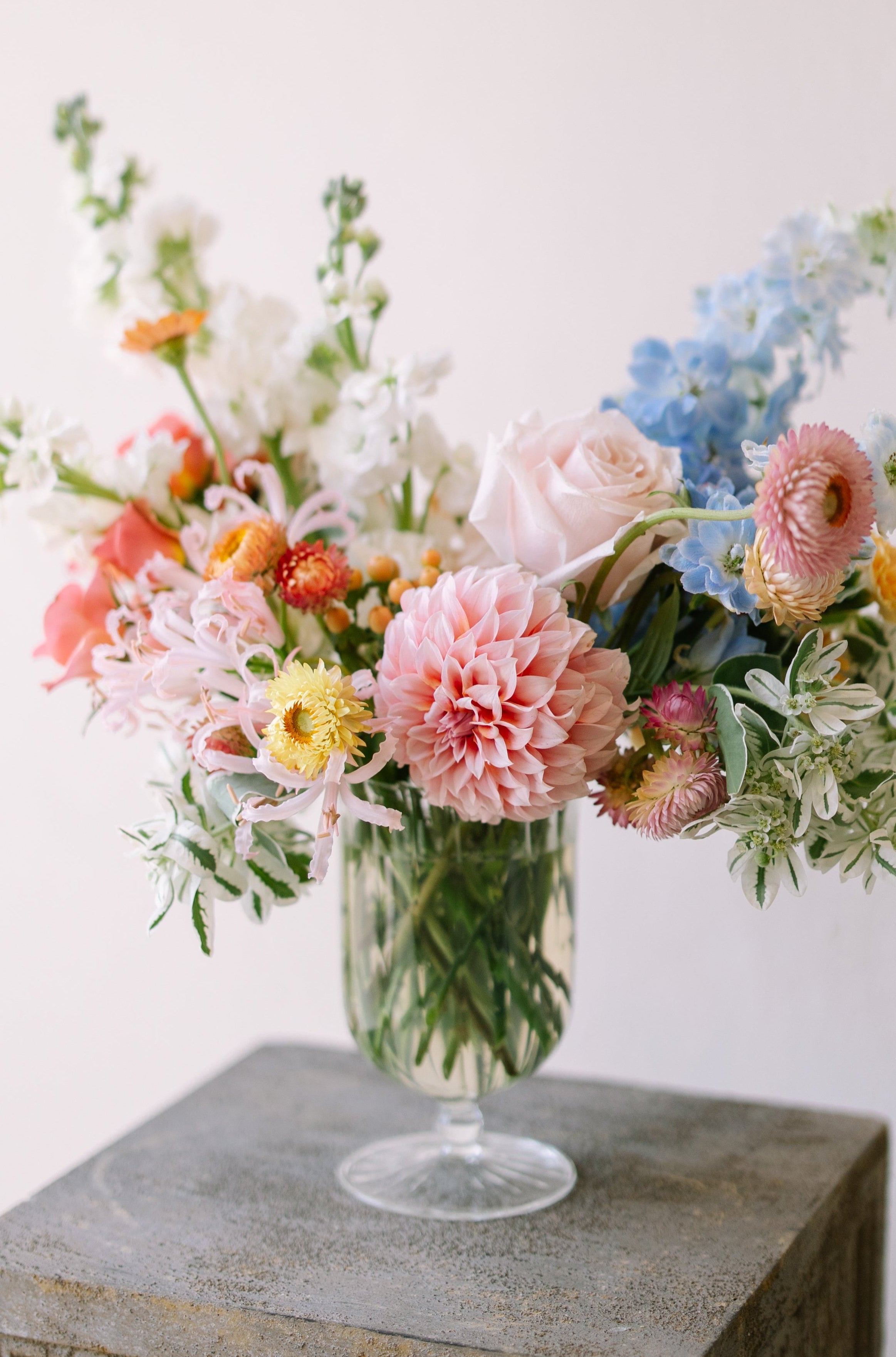 Garden flower arrangement in a footed glass vase.