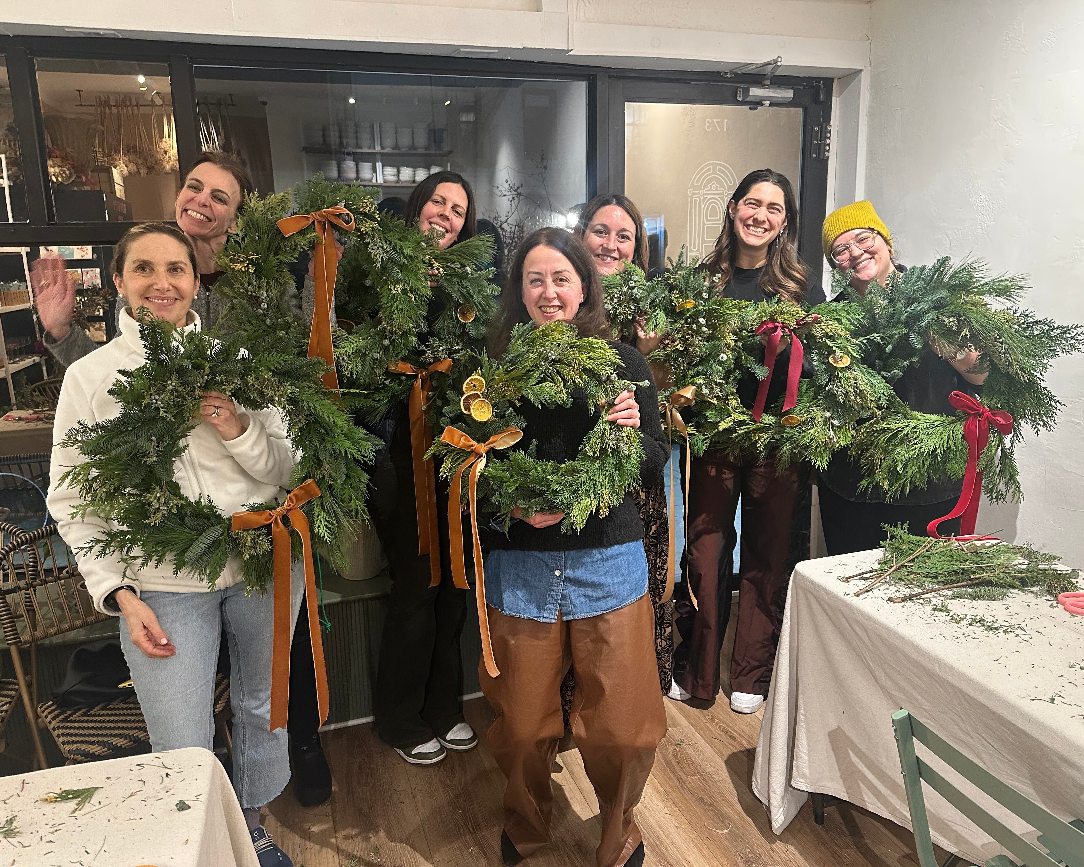 People holding Christmas wreaths in a store setting