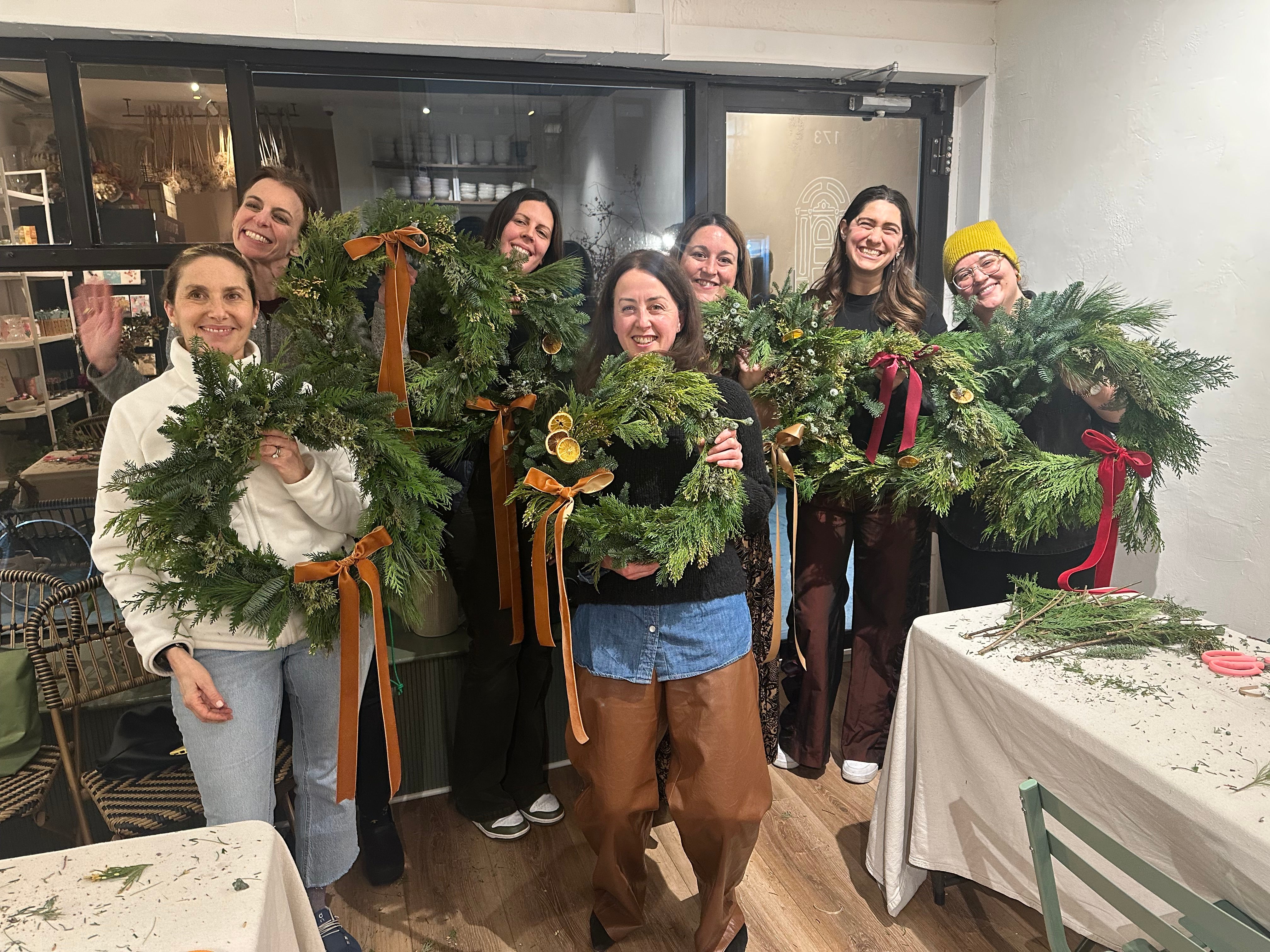 People holding Christmas wreaths in a store setting