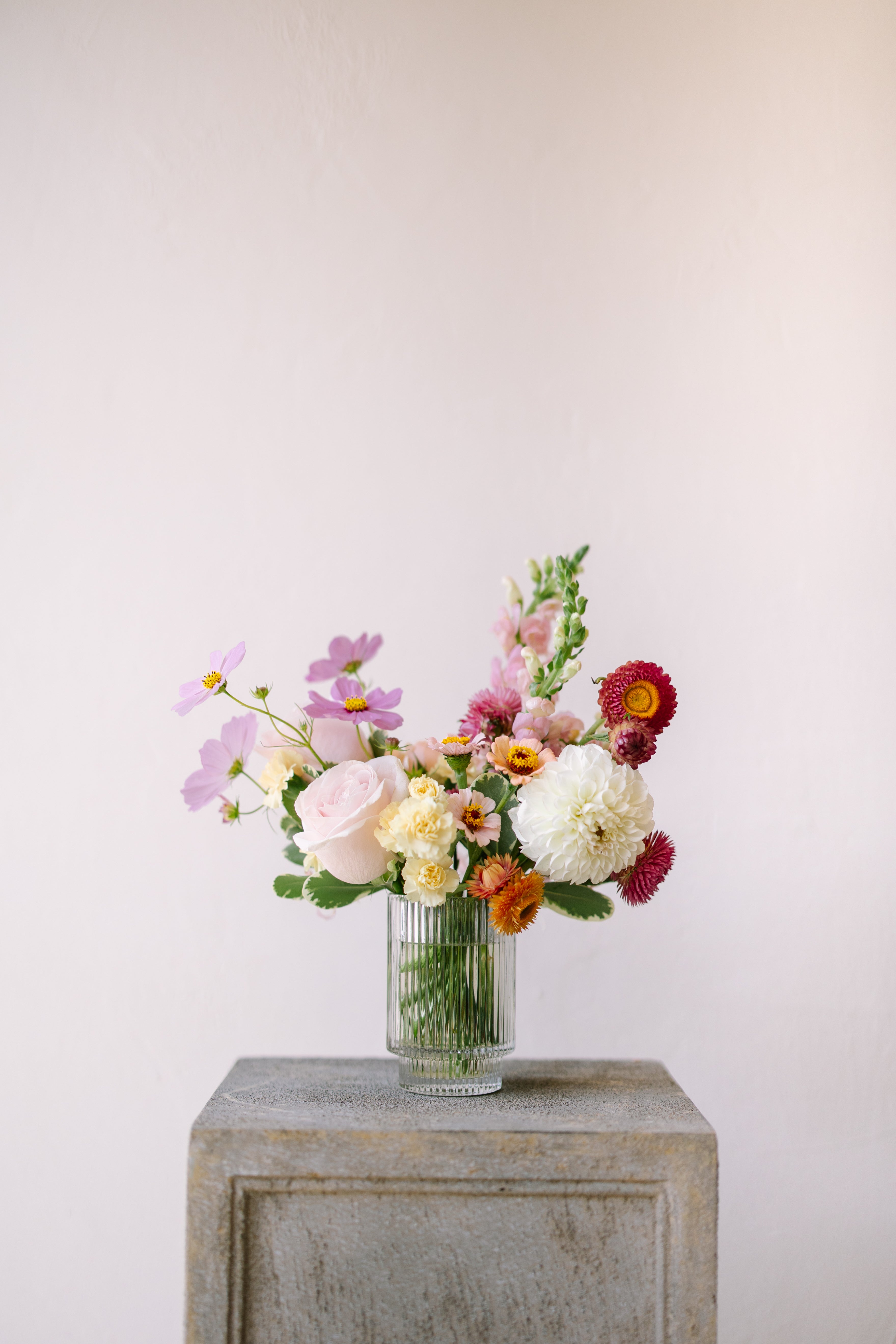 Small flower arrangement in ribbed glass vessel.