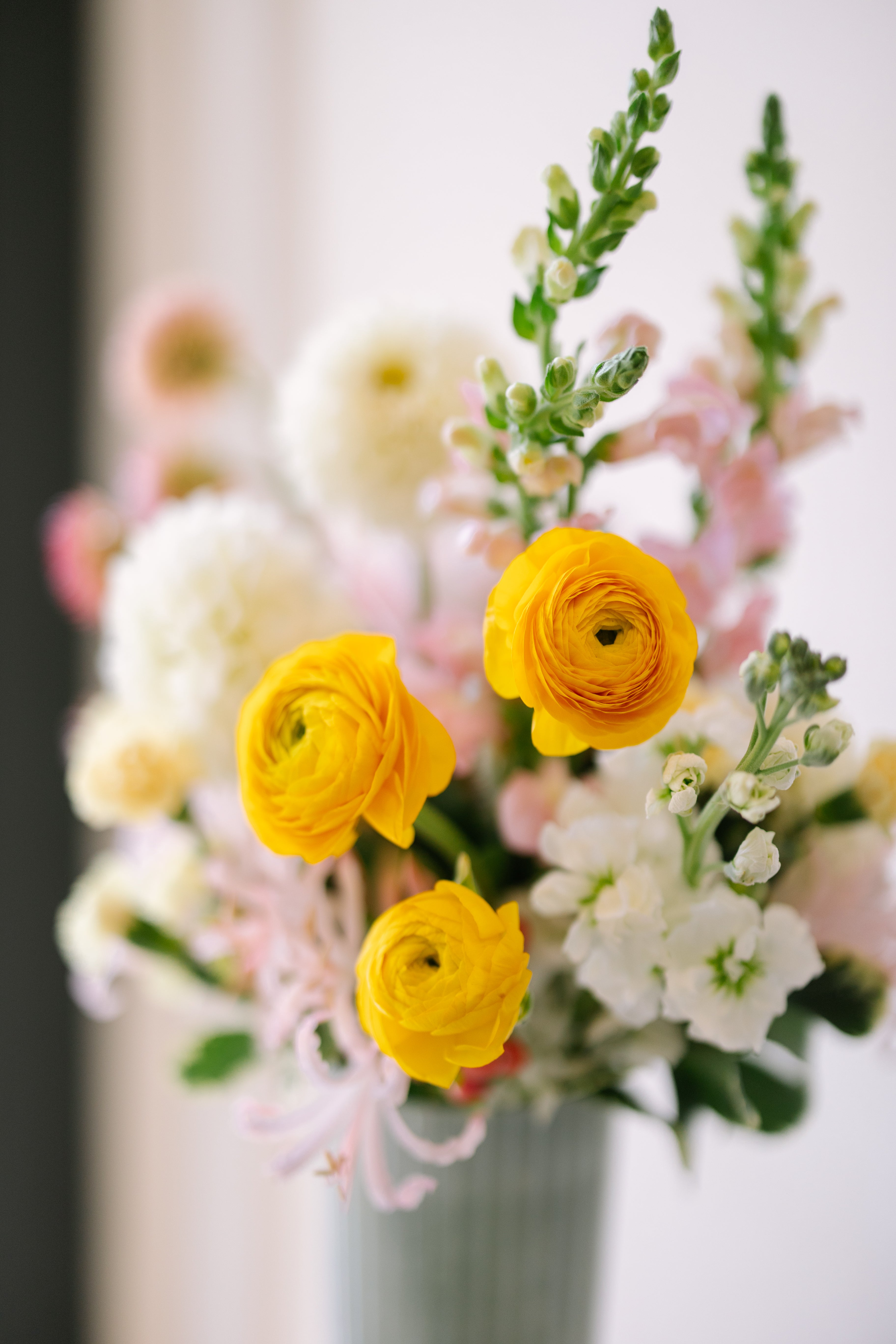 Tall garden flower arrangement in white footed vase.