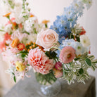 Garden flower arrangement in a footed glass vase.