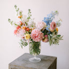 Garden flower arrangement in a footed glass vase.