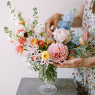 Garden flower arrangement in a footed glass vase.