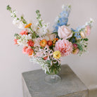 Garden flower arrangement in a footed glass vase.